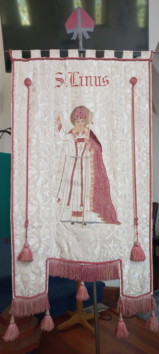 St Linus Banner
The Rev’d W Clarke Hudson left a memorandum concerning his choice of Saint Linus as patron saint, in which he wrote: 

“St Linus was chosen as the patron saint of this church because he was a Briton, almost the first Briton mentioned in history, and certainly the first British saint.  He was the son of King Caradoc, who, tradition relates, was converted to Christianity by the mission to Glastonbury about the middle of the first century.  King Caradoc was conquered and carried captive with his family to Rome by the Emperor Claudius, but his noble demeanour so affected Claudius that the latter gave Caradoc his liberty, and that of his whole family, who thus became Roman citizens.  Linus was the first Bishop of Rome, sometime between 56 and 80 AD.  St Paul, in his second Epistle to Timothy , Chapter 4, verse 21, numbers Linus, Claudia and Pudens (her husband) among the early Christians.  The Apostolical Constitutions tell us that Linus and Claudius were brother and sister.  We learn from tradition that Linus was beheaded by order of Saturninus for refusing to give up the faith”

